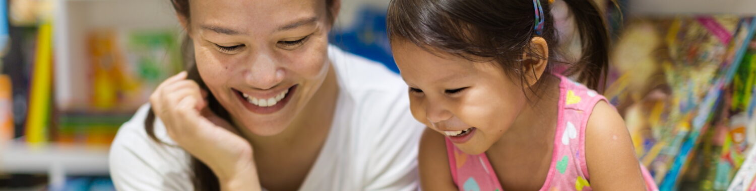 mother reading book with daughter in library