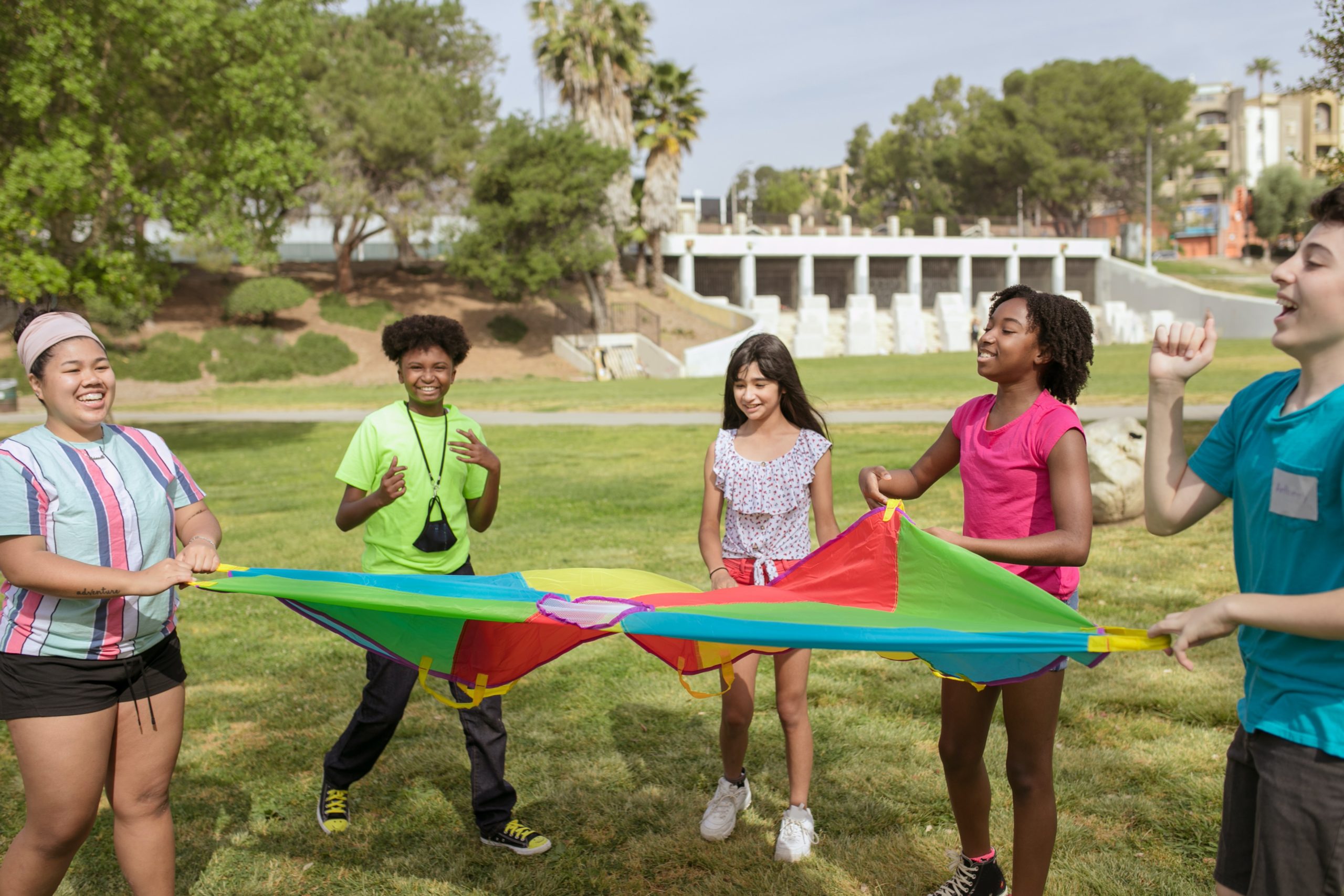 Middle school students play a game with a parachute outside.