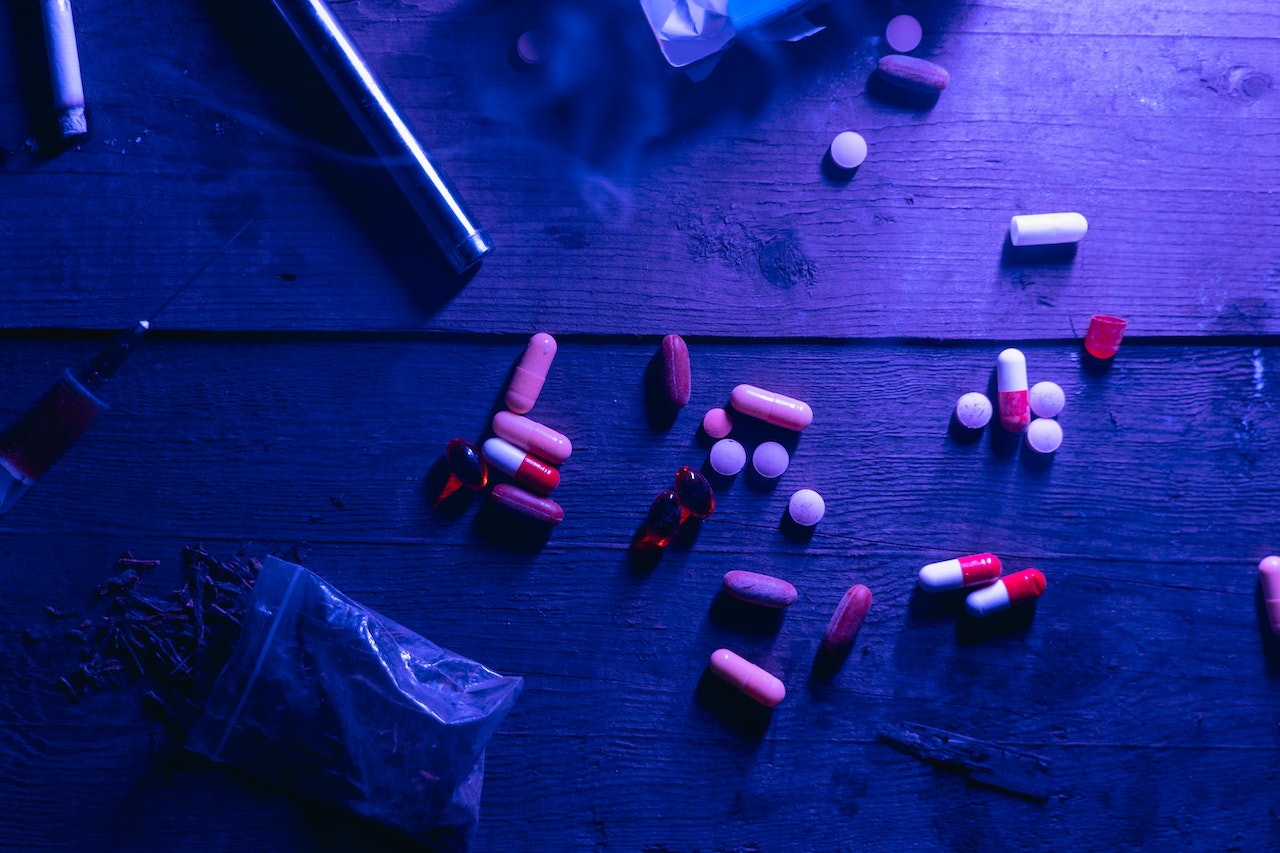 A variety of colored pills scattered on a wooden tabletop.