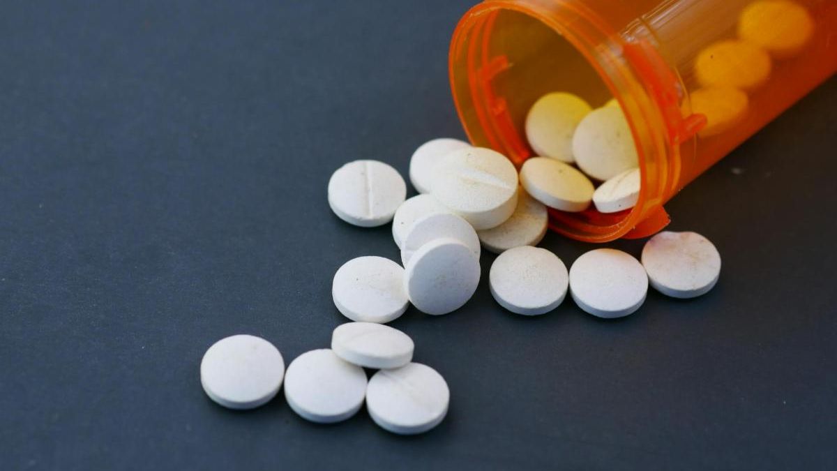 open pill bottle spilled onto dark counter