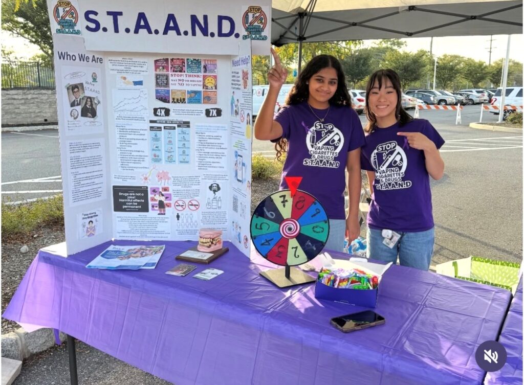 S.T.A.A.N.D student leaders host a vaping prevention table at a community health event in Piscataway, engaging youth with educational materials and an interactive activity.