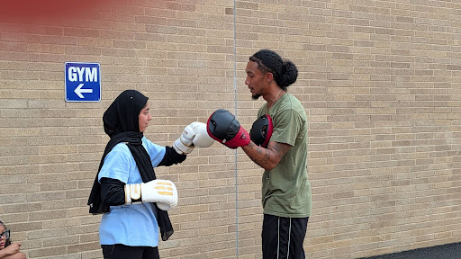 Student wearing boxing gloves practicing a contact-free boxing drill with a Pivotal Point mentor.