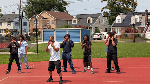 Group of students practicing boxing stances and movements together on an outdoor track.